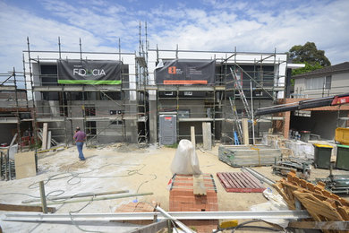 Design ideas for a large modern three-storey stucco exterior in Sydney with a flat roof.
