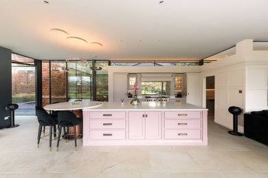 This is an example of an expansive contemporary galley open plan kitchen in Essex with a single-bowl sink, shaker cabinets, grey cabinets, engineered stone countertops, metallic splashback, glass sheet splashback, stainless steel appliances, ceramic flooring, an island, beige floors and white worktops.
