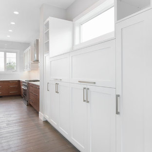 Photo of a large contemporary single-wall kitchen pantry in Calgary with an undermount sink, shaker cabinets, stainless steel cabinets, quartz benchtops, white splashback, ceramic splashback, stainless steel appliances, dark hardwood floors and with island.