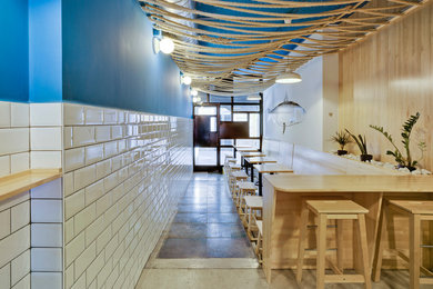 Imagen de comedor mediterráneo pequeño abierto con paredes azules, suelo de cemento y suelo gris