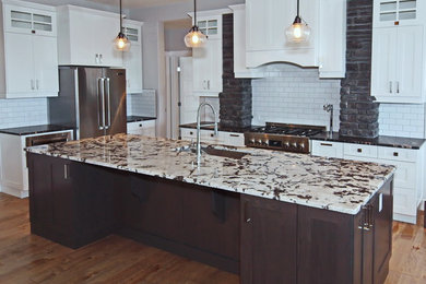 This is an example of a transitional single-wall kitchen in Calgary with an undermount sink, shaker cabinets, light wood cabinets, granite benchtops, subway tile splashback, stainless steel appliances, light hardwood floors, with island and white splashback.