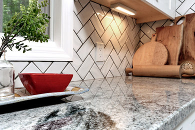 Inspiration for a mid-sized transitional u-shaped slate floor and gray floor eat-in kitchen remodel in Boston with an undermount sink, shaker cabinets, white cabinets, granite countertops, white backsplash, porcelain backsplash, stainless steel appliances, an island and gray countertops