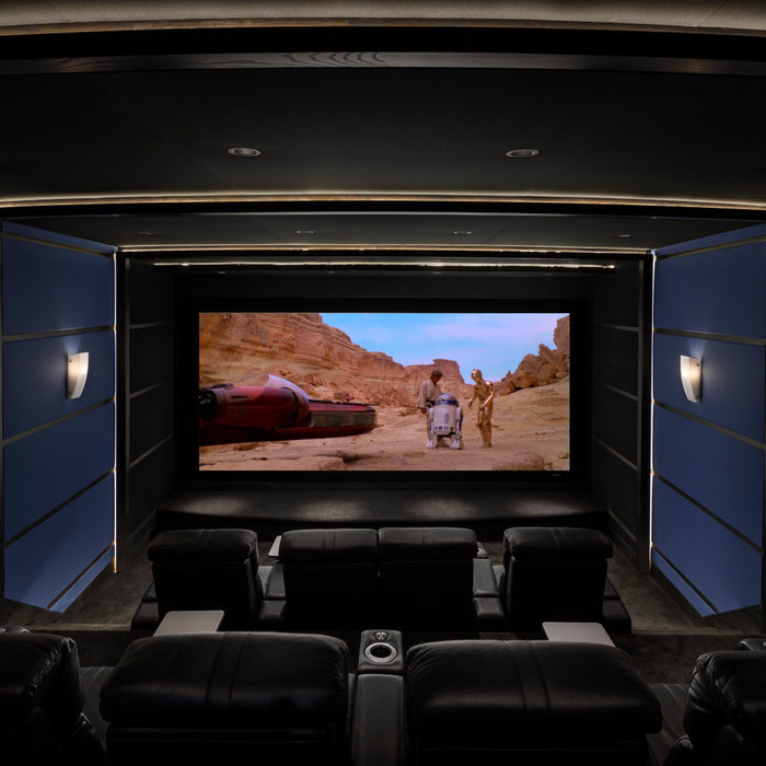 Home theater - large industrial enclosed carpeted and black floor home theater idea in Detroit with blue walls and a media wall