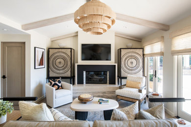 Photo of a beach style living room in Los Angeles with beige walls, light hardwood floors, a ribbon fireplace, a wall-mounted tv and exposed beam.