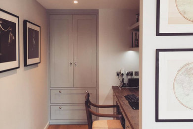 Photo of a large contemporary study room in London with grey walls, light hardwood floors and a built-in desk.