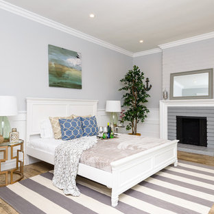Großes Klassisches Gästezimmer mit grauer Wandfarbe, hellem Holzboden, Kamin und Kaminumrandung aus Backstein in Los Angeles