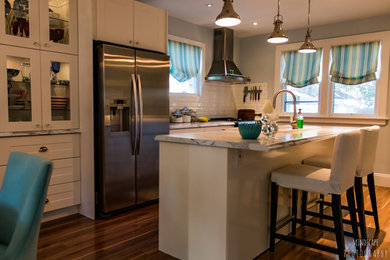 Inspiration for a mid-sized beach style galley eat-in kitchen in Toronto with a farmhouse sink, shaker cabinets, white cabinets, laminate benchtops, white splashback, subway tile splashback, stainless steel appliances, light hardwood floors and with island.