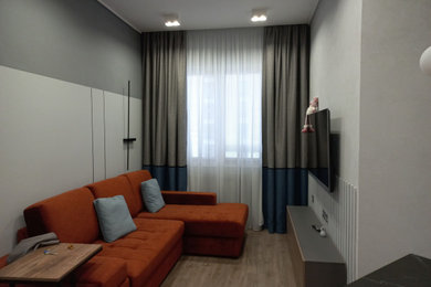 Diseño de salón gris y blanco actual de tamaño medio con paredes grises, suelo laminado, televisor colgado en la pared y suelo marrón