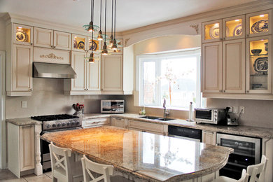 Large elegant l-shaped porcelain tile kitchen pantry photo in Toronto with an undermount sink, raised-panel cabinets, beige cabinets, granite countertops, beige backsplash, stone slab backsplash, stainless steel appliances and an island