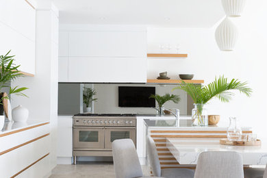 Inspiration for a large contemporary l-shaped kitchen pantry in Gold Coast - Tweed with an undermount sink, flat-panel cabinets, white cabinets, quartz benchtops, grey splashback, mirror splashback, stainless steel appliances, porcelain floors and beige floor.