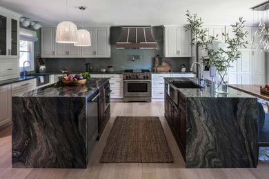 Example of a huge transitional l-shaped light wood floor and beige floor eat-in kitchen design in Boston with an undermount sink, shaker cabinets, white cabinets, quartzite countertops, gray backsplash, glass tile backsplash, stainless steel appliances and two islands