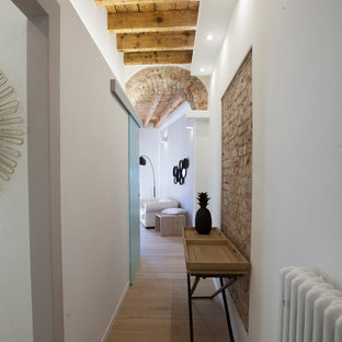 Diseño de hall bohemio, de tamaño medio, con paredes blancas, suelo de madera clara, puerta pivotante, puerta blanca y suelo beige