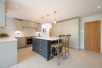 This is an example of a large traditional u-shaped open plan kitchen in Hertfordshire with a drop-in sink, shaker cabinets, grey cabinets, quartzite benchtops, white splashback, stainless steel appliances, with island and white benchtop.