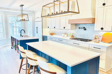 Large beach style single-wall eat-in kitchen in Detroit with an undermount sink, recessed-panel cabinets, white cabinets, quartz benchtops, metallic splashback, glass tile splashback, panelled appliances, light hardwood floors, multiple islands, brown floor and white benchtop.