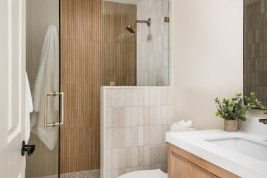Alcove shower - small transitional 3/4 multicolored tile and porcelain tile porcelain tile, multicolored floor and single-sink alcove shower idea in Charlotte with furniture-like cabinets, medium tone wood cabinets, a two-piece toilet, multicolored walls, an integrated sink, quartz countertops, a hinged shower door, white countertops, a niche and a freestanding vanity