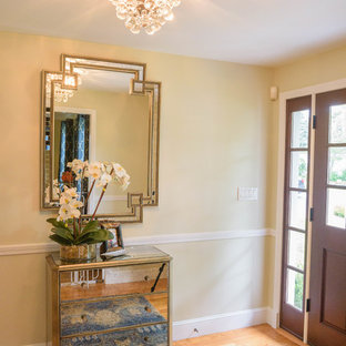 Aménagement d'une petite porte d'entrée éclectique avec un mur beige, un sol en bois clair, une porte simple, une porte marron et un sol marron.