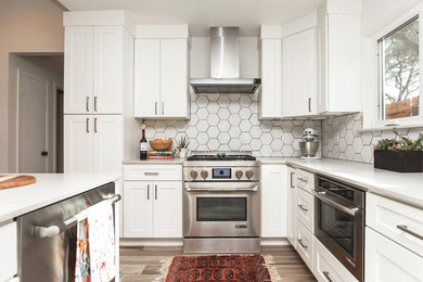 Kitchen - cottage laminate floor and gray floor kitchen idea in Austin with an undermount sink, white cabinets, quartzite countertops, white backsplash, ceramic backsplash, stainless steel appliances, an island and white countertops