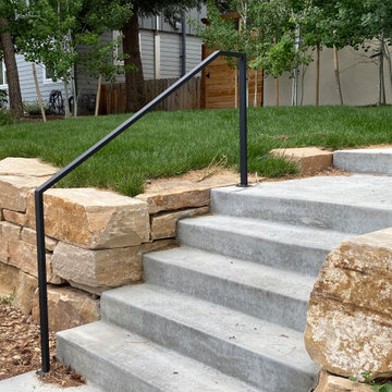 Mountain inspired minimalist boulder retaining walls and plantings.