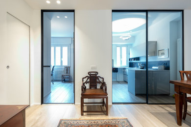 This is an example of a mid-sized contemporary foyer in Milan with white walls, porcelain floors, a single front door, a white front door and recessed.