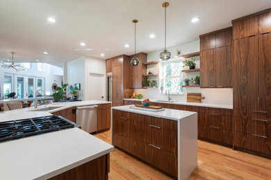 Design ideas for a contemporary u-shaped kitchen in Orlando with an undermount sink, flat-panel cabinets, medium wood cabinets, stainless steel appliances, medium hardwood floors, with island, brown floor and white benchtop.