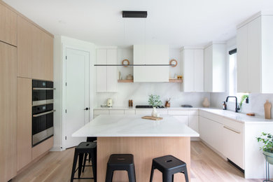 Example of a mid-sized danish u-shaped light wood floor and brown floor open concept kitchen design in Other with an undermount sink, flat-panel cabinets, white cabinets, quartz countertops, white backsplash, quartz backsplash, paneled appliances, an island and white countertops