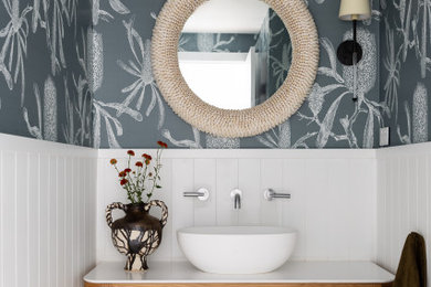 Trendy gray floor, wainscoting and wallpaper powder room photo in Sydney with gray walls, a vessel sink, white countertops and a freestanding vanity