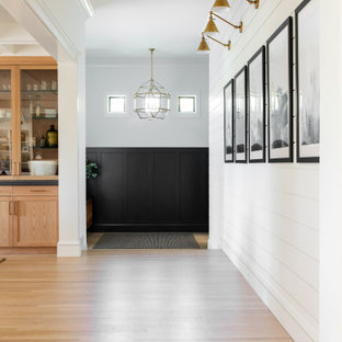 サクラメントの片開きドアカントリー風おしゃれな玄関ホール (黒い壁、淡色無垢フローリング、黒いドア) の写真