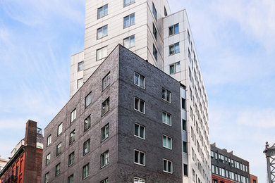 Modelo de fachada gris contemporánea grande de tres plantas con revestimiento de ladrillo y tejado plano