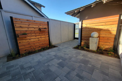 Example of a mid-sized minimalist courtyard concrete paver patio design in Orange County with no cover
