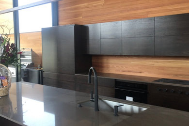 Inspiration for a huge modern single-wall porcelain tile eat-in kitchen remodel in Other with a single-bowl sink, flat-panel cabinets, dark wood cabinets, quartz countertops, brown backsplash, wood backsplash, paneled appliances, an island and brown countertops