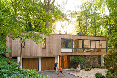 This is an example of a large midcentury two-storey exterior in New York with wood siding and a flat roof.