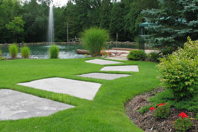 This is an example of a large traditional backyard stone water fountain landscape in Toronto.