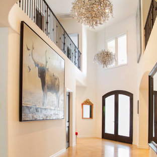 Réalisation d'un grand hall d'entrée bohème avec un mur blanc, un sol en travertin, une porte double et une porte en bois foncé.