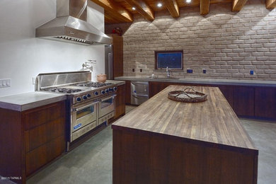 Inspiration for a large contemporary single-wall concrete floor open concept kitchen remodel in Phoenix with a drop-in sink, flat-panel cabinets, medium tone wood cabinets, concrete countertops, stainless steel appliances and an island