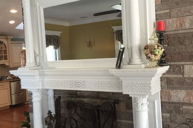 Example of a large ornate formal and open concept medium tone wood floor and brown floor living room design in New York with a wood fireplace surround, a concealed tv, green walls and a standard fireplace