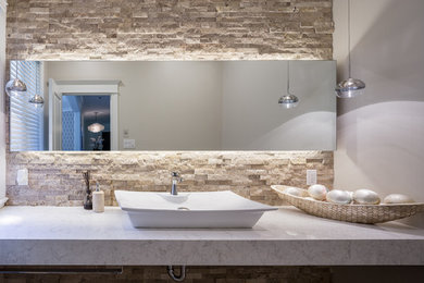 This is an example of a small contemporary powder room in Ottawa with beige tile, beige walls, a vessel sink, engineered quartz benchtops, a one-piece toilet, travertine, travertine floors and beige floor.