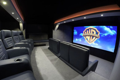 Photo of a large contemporary enclosed home cinema in Other with grey walls, carpet, a projector screen and grey floors.