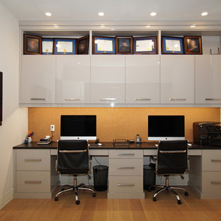 Photo of a small modern home studio in Other with grey walls, laminate floors and a built-in desk.