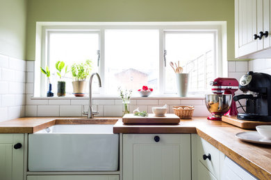 Inspiration for a small traditional grey and cream l-shaped enclosed kitchen in Essex with shaker cabinets, white cabinets, no island, a belfast sink, wood worktops, white splashback, ceramic splashback and ceramic flooring.