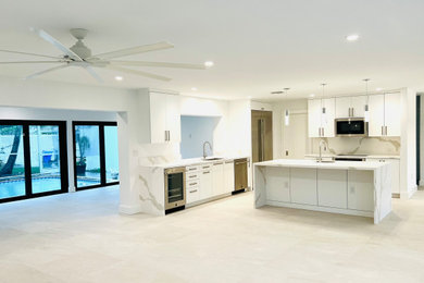 Example of a minimalist l-shaped kitchen design in Miami with a single-bowl sink, white cabinets, quartz countertops, quartz backsplash, stainless steel appliances, flat-panel cabinets and an island