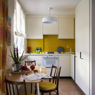 На фото: с невысоким бюджетом маленькие угловые кухни - столовые в стиле фьюжн с врезной раковиной, плоскими фасадами, столешницей из акрилового камня, желтым фартуком, фартуком из плитки мозаики, белой техникой, полом из керамогранита, коричневым полом, бежевыми фасадами и бежевой столешницей без острова