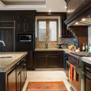 Inspiration pour une grande arrière-cuisine ethnique en L avec un évier encastré, un placard avec porte à panneau surélevé, des portes de placard en bois sombre, un plan de travail en granite, une crédence beige, un électroménager en acier inoxydable, un sol en marbre et un îlot central.