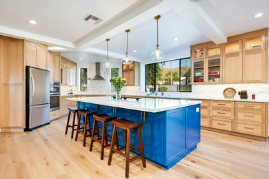 Example of a large trendy light wood floor and beige floor kitchen design in Phoenix with an undermount sink, shaker cabinets, light wood cabinets, quartz countertops, multicolored backsplash, subway tile backsplash, stainless steel appliances, an island and white countertops