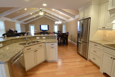 Mid-sized elegant l-shaped medium tone wood floor and brown floor eat-in kitchen photo in Baltimore with a double-bowl sink, raised-panel cabinets, white cabinets, granite countertops, beige backsplash, ceramic backsplash, stainless steel appliances and an island