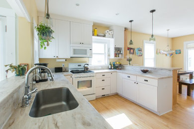 This is an example of an u-shaped eat-in kitchen in Minneapolis with recessed-panel cabinets, white cabinets, granite benchtops and no island.