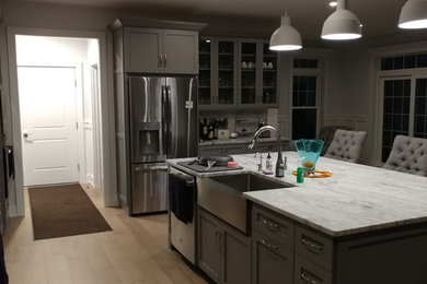 Kitchen pantry - mid-sized contemporary single-wall light wood floor and brown floor kitchen pantry idea in Philadelphia with stainless steel appliances, an island, a farmhouse sink, shaker cabinets, gray cabinets and soapstone countertops
