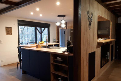 Cette image montre une cuisine ouverte noire et bois design en U avec un évier 1 bac, un plan de travail en stratifié et aucun îlot.