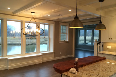 L-shaped kitchen photo in Boston with white cabinets, granite countertops, beige backsplash, glass tile backsplash and an island