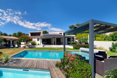 Réalisation d'un grand piscine avec aménagement paysager avant design avec une terrasse en bois.