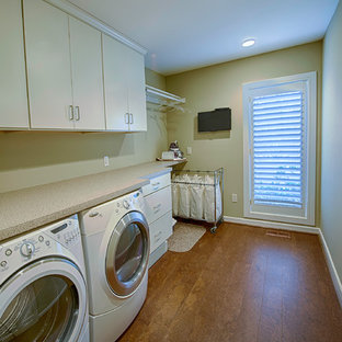 Inspiration for a traditional single-wall utility room in Philadelphia with flat-panel cabinets, white cabinets, beige walls, cork flooring and a side by side washer and dryer.